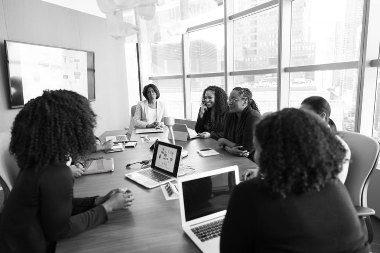 Black and white image of a team round a board table - How much does a content marketing consultant cost - Copify blog