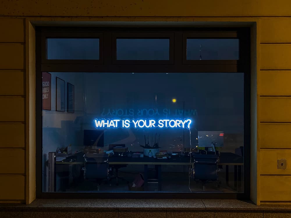 Neon light spelling 'what is your story?' - 3 storytelling copywriting examples - Copify blog