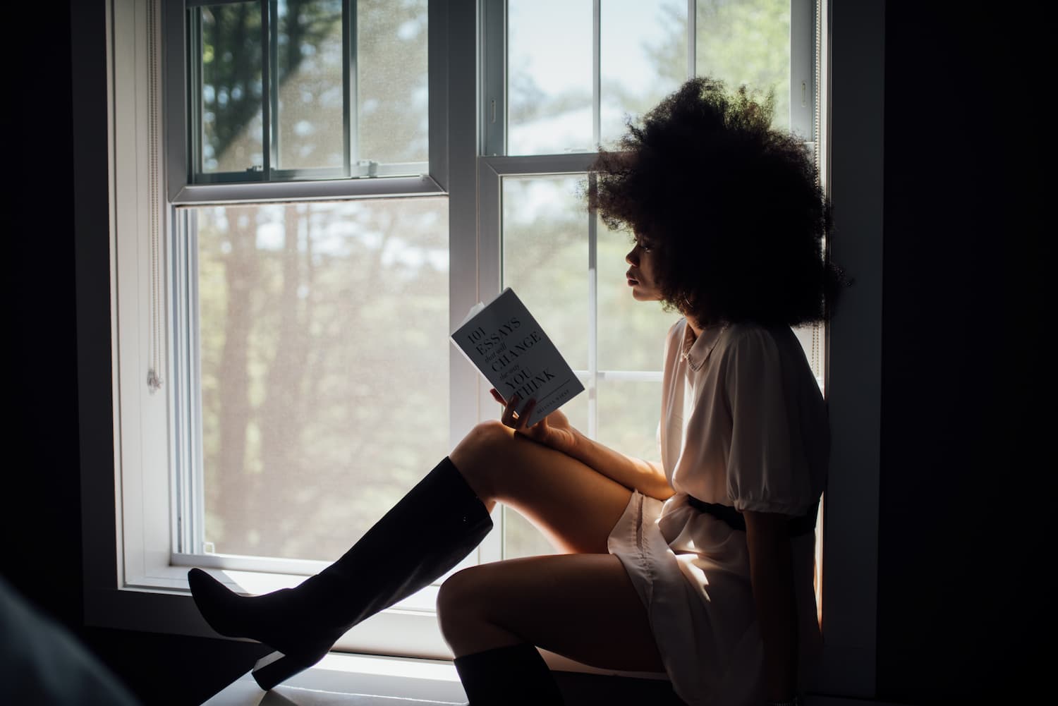 Woman reading on a window ledge - 5 best books to learn copywriting - Copify blog
