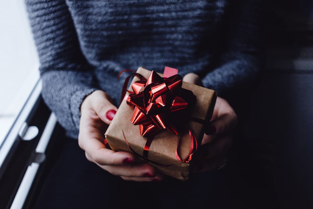 Woman holding gift wrapped present - 5 perfect gifts for copywriters this Christmas - Copify blog
