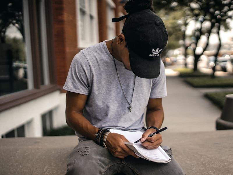 Man in cap writing - 6 freelance writing opportunities for beginners - Copify blog