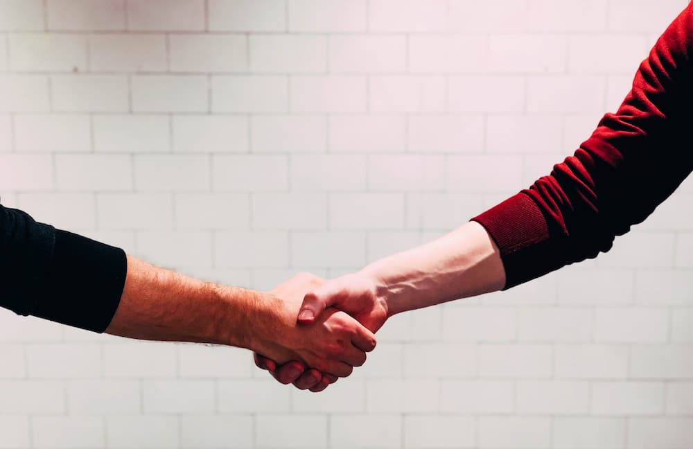 Two people shaking hands - 6 things to know before hiring a writer for your blog - Copify blog