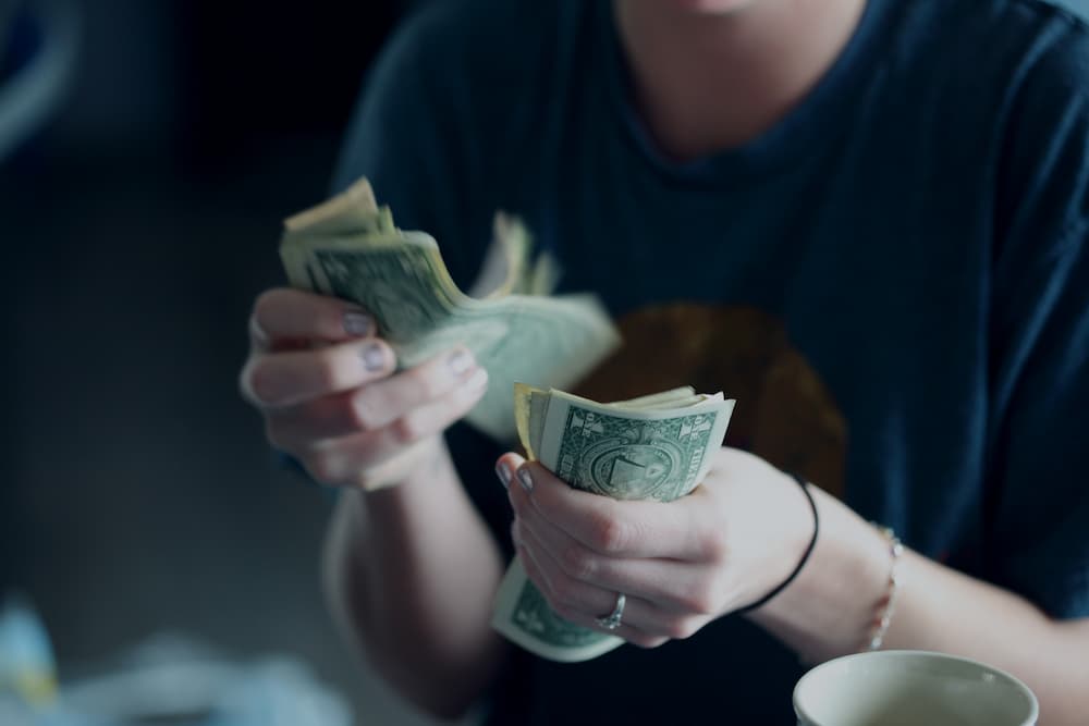 Someone counting dollar bills - How much does content creation cost - Copify blog