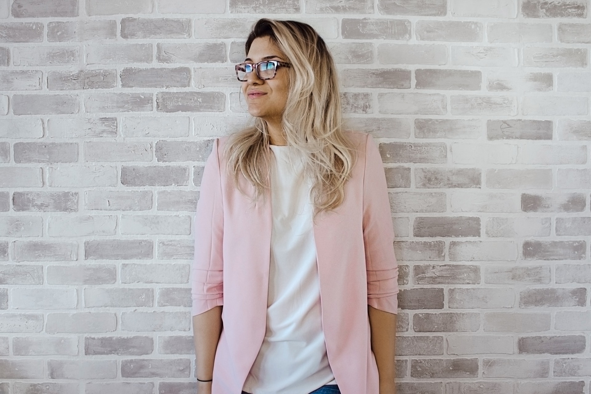 Professional woman against brick background - What is a junior copywriter and what do they do? - Copify Blog 1